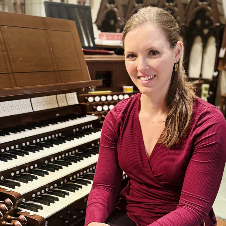 Woman sitting next to an organ and smiling